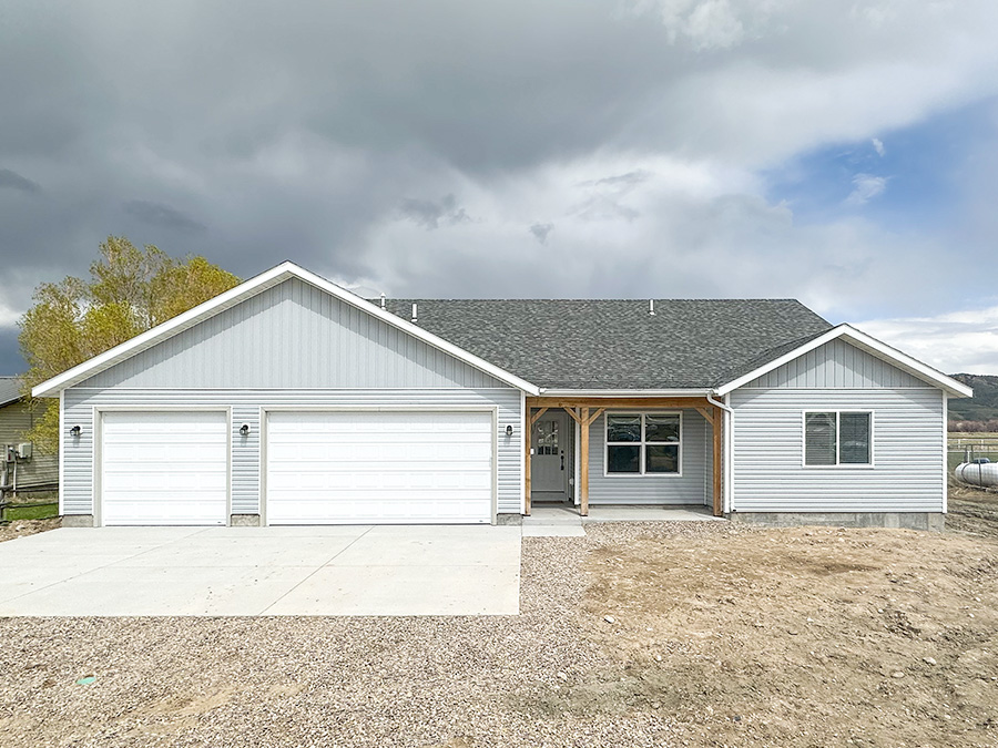 Charming ranch home with 3-car garage, classic grey and black color scheme with accenting white garage doors.